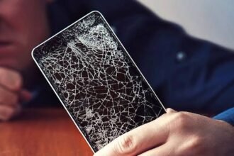 Person holding a smartphone with a severely cracked screen