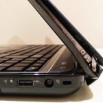 Close-up of a broken laptop hinge with the screen detached from the base