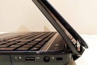 Close-up of a broken laptop hinge with the screen detached from the base
