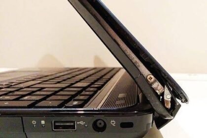 Close-up of a broken laptop hinge with the screen detached from the base