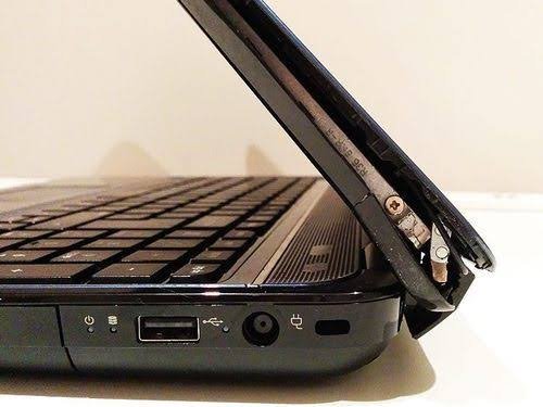 Close-up of a broken laptop hinge with the screen detached from the base