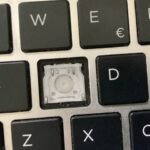 Close-up of a laptop keyboard with the S key removed, showing the switch mechanism underneath