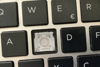 Close-up of a laptop keyboard with the S key removed, showing the switch mechanism underneath