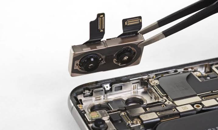 Technician removing a smartphone dual camera module with tweezers during repair